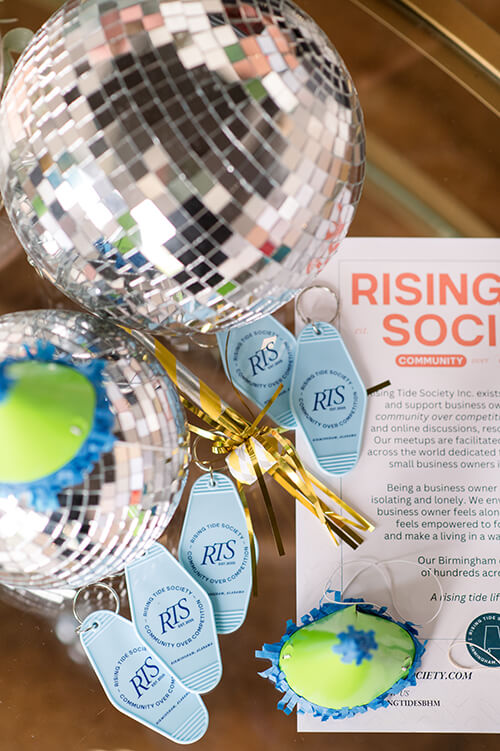 Rising Tide hotel keychains with disco balls, party hats, and noise makers in a flat lay